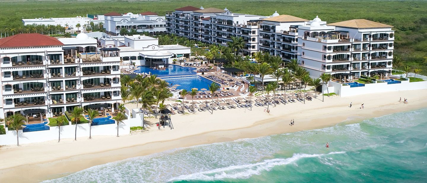 Aerial view of beachfront resort with pools and sand beach